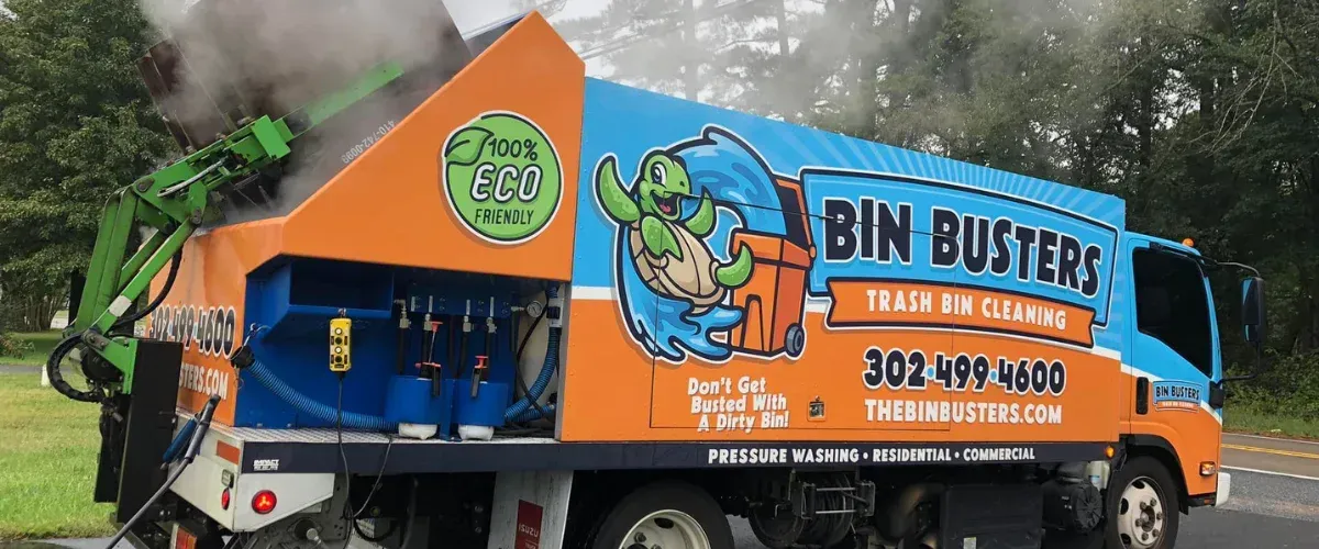 A Bin Busters truck with "100% ECO FRIENDLY" logo and a turtle mascot, cleaning a bin with steam. 