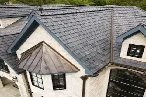Aerial view of luxury home with dark impact-resistant shingles and copper roof accents in Blaine