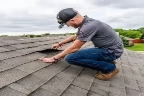 Roof inspector examining a lifted shingle during a residential inspection by Blaine Roofing