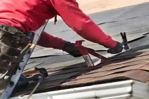 Roofer removing old shingles with a pry bar during repair work by Blaine Roofing