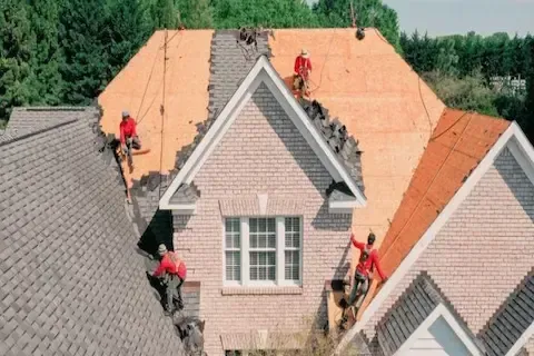 Aerial view of roofing crew replacing shingles on a two-story brick home in Blaine