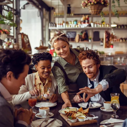 Chef at a restaurant serving a dish to happy customers