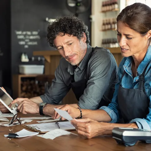 two restaurant owners eating a a table review bills and verhead