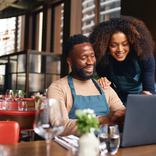 Two happy restaurant owners looking over a computer