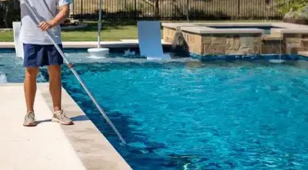 Canyon Lake Pool Service team member brushing pool walls with a telescoping pole