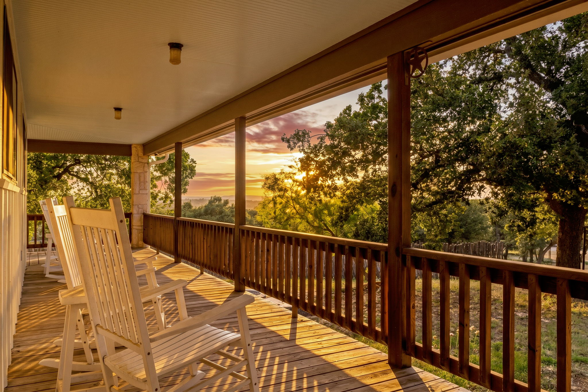 Covered porch with rocking chairs looking out over a Texas Hill Country view at sunset