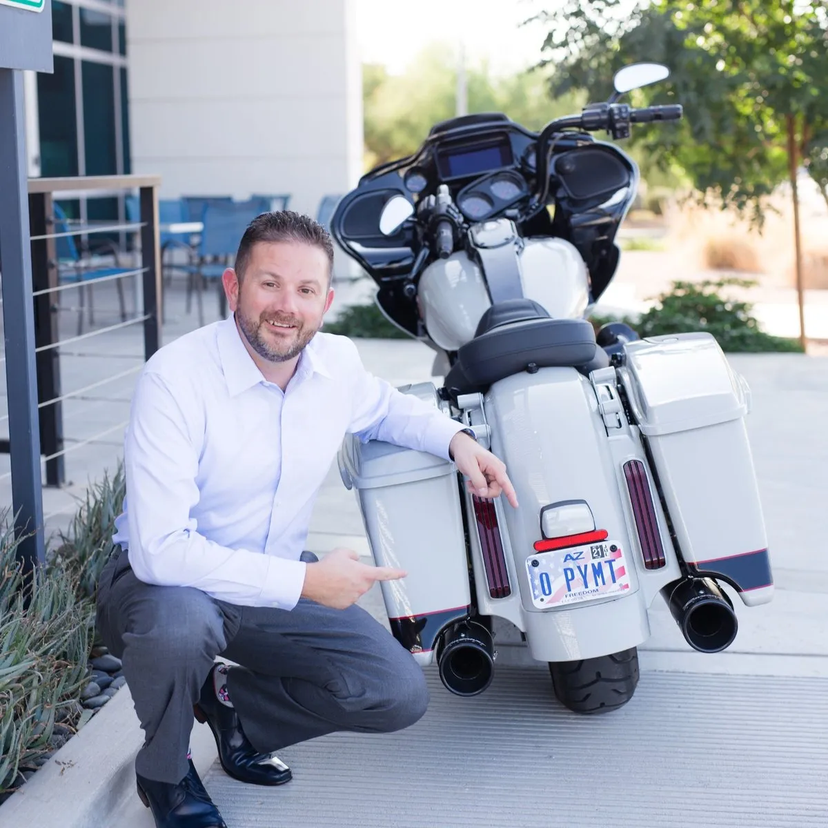 Streamlined Business Solutions owner kneeling beside a motorcycle with an Arizona license plate reading 0 PYMT