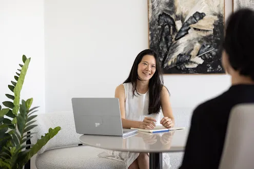 Sheryl Ang conducting an intimate therapeutic coaching session in a serene, warm office setting
