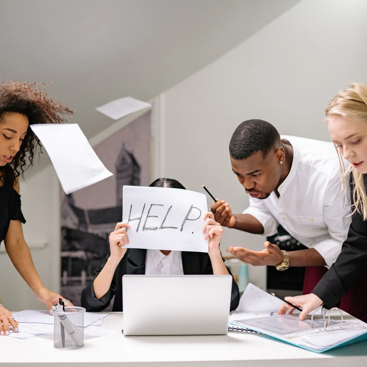 woman-holding-help-sign-while-coworkers-try-to-interrupt-her