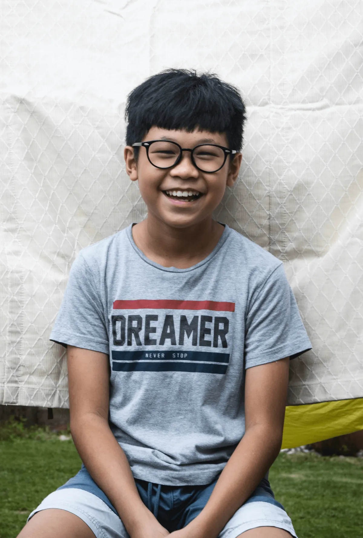 young boy with glasses and a big smile seated