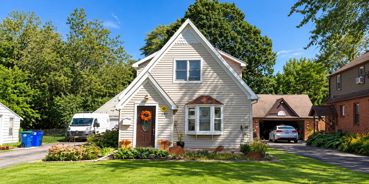 Two-story home with landscaped front yard, driveway, and detached garage.