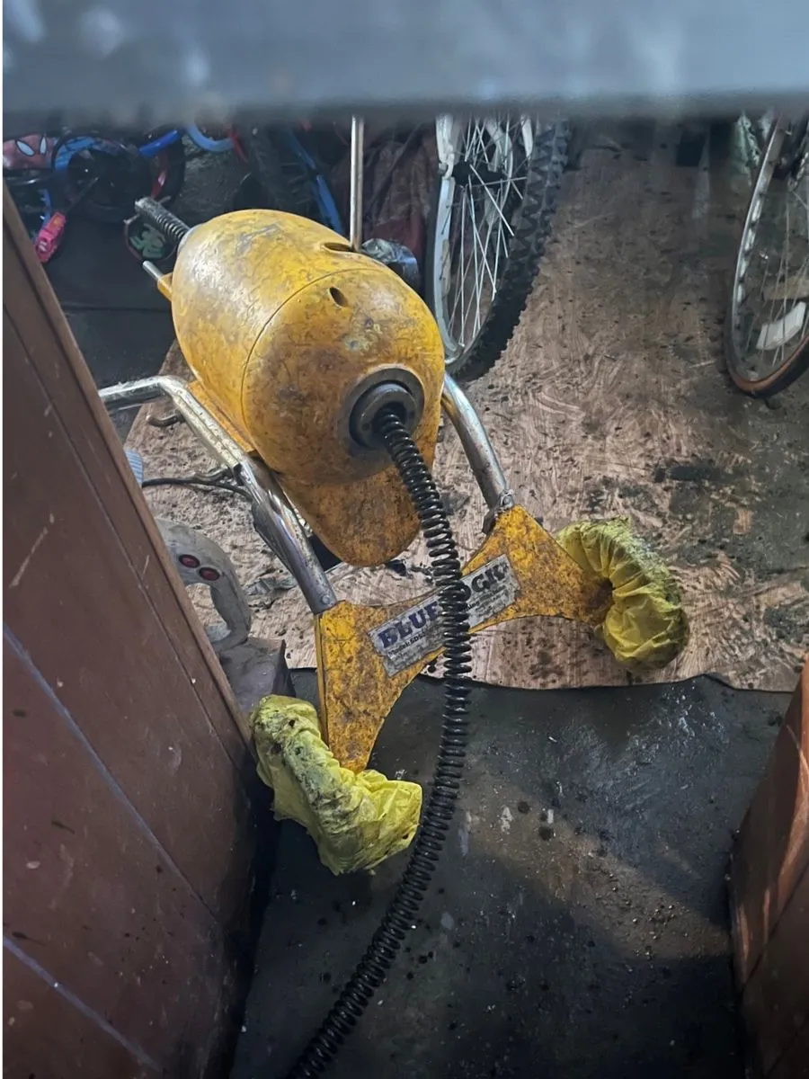 Yellow drain cleaning machine with sewer cable used for residential drain cleaning.
