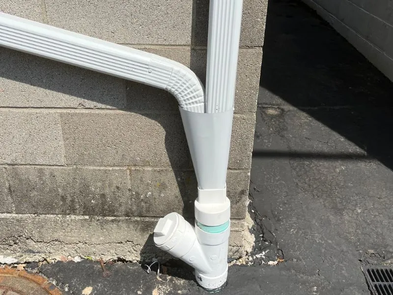 Exterior downspout and drainage piping installed alongside a home in Tonawanda, NY