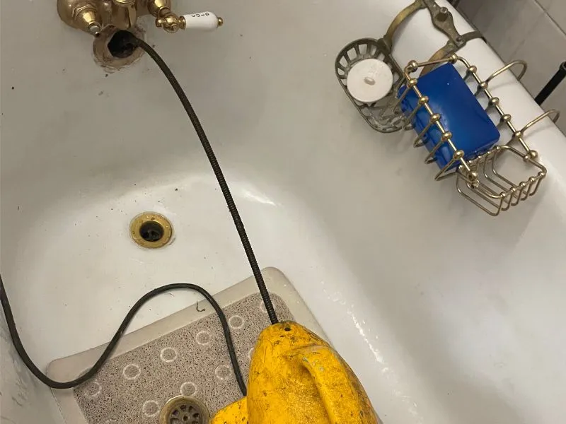 Professional drain cleaning equipment clearing a bathtub drain in a Buffalo, NY home