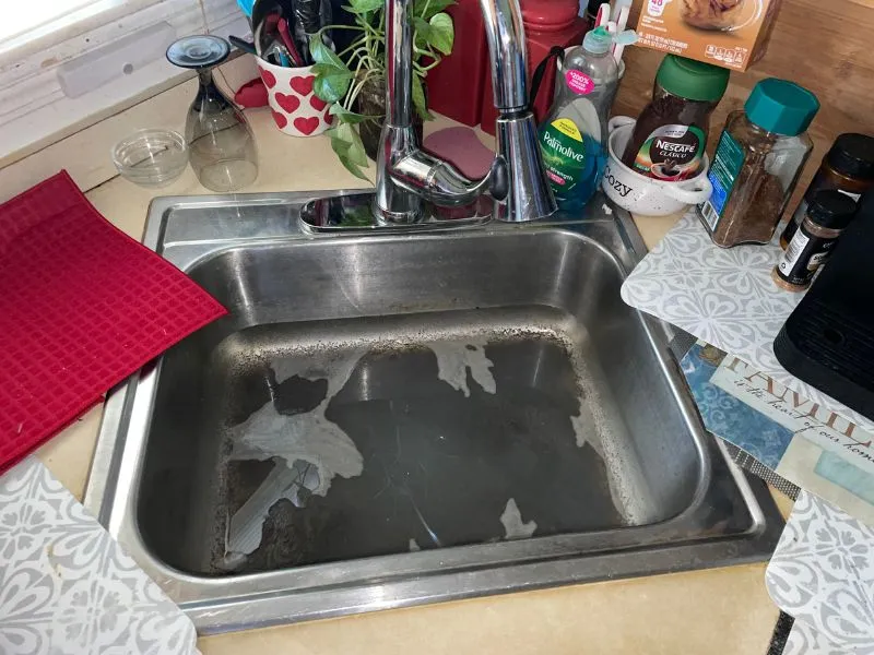 Kitchen sink filled with standing water caused by a clogged drain.