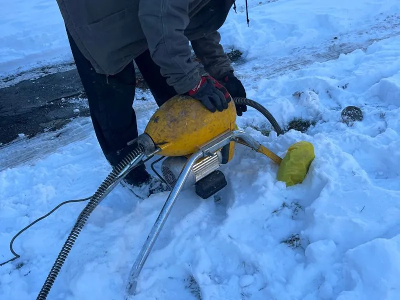 WorryFree Home Services technician using professional sewer cleaning equipment outdoors during winter in Buffalo, NY