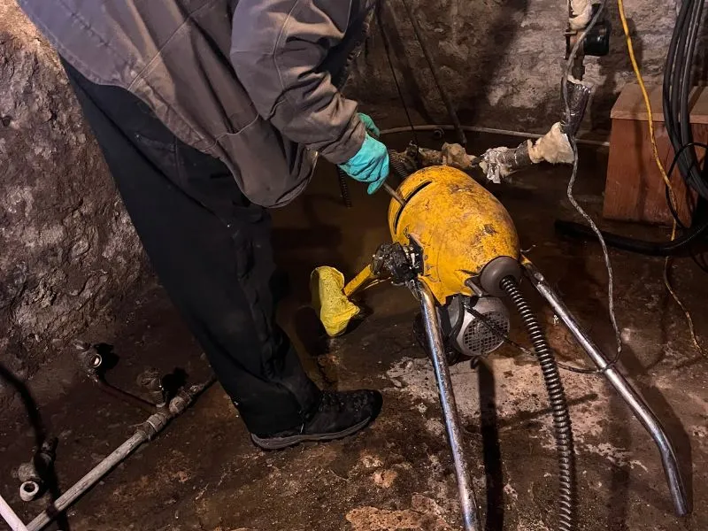 WorryFree technician operating sewer cleaning equipment inside a basement to restore wastewater flow