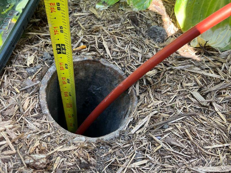 Sewer inspection camera cable entering an outdoor sewer cleanout to investigate drainage problems