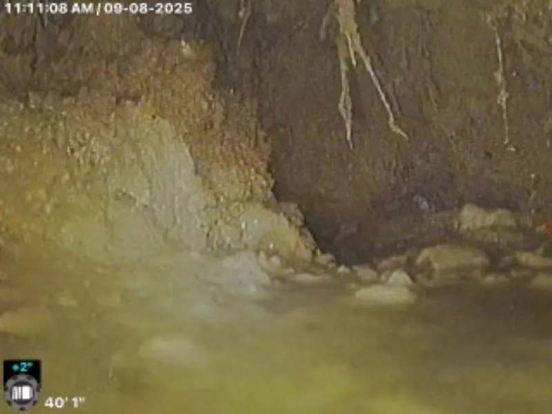 Sewer camera inspection showing the inside of a sewer pipe with sediment buildup and possible pipe damage