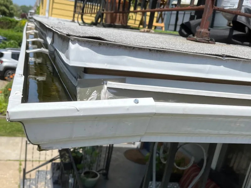 Back-pitched rain gutter holding standing water instead of draining properly on a Buffalo, NY home.