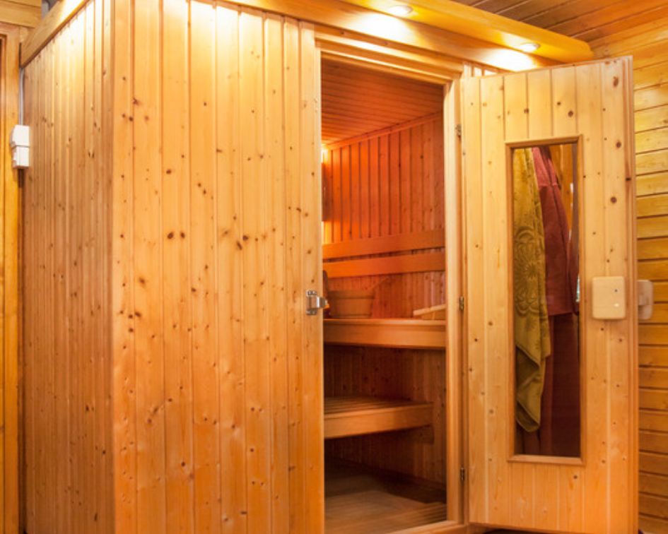 Compact pre-built sauna installed in corner with accessories