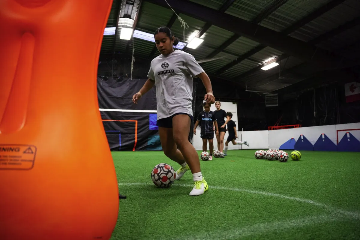 Kids playing soccer with a coach during practice