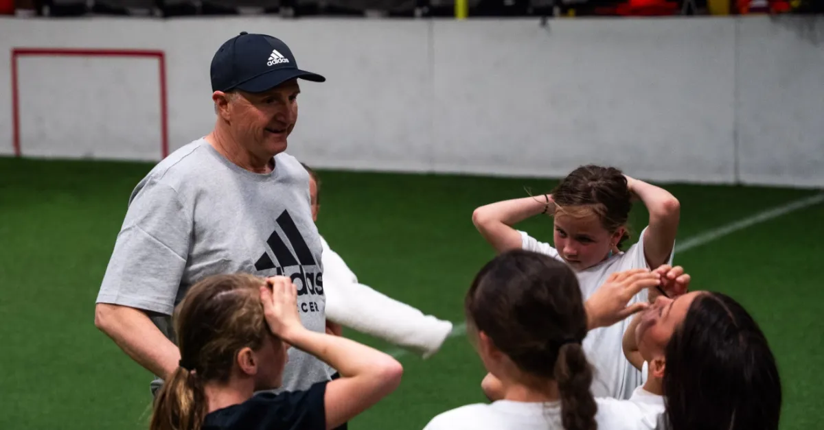 Kids playing soccer with a coach during practice