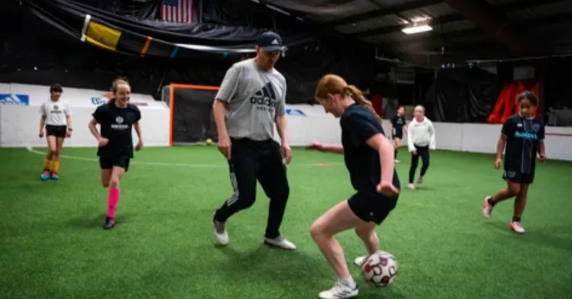 Kids playing soccer with a coach during practice