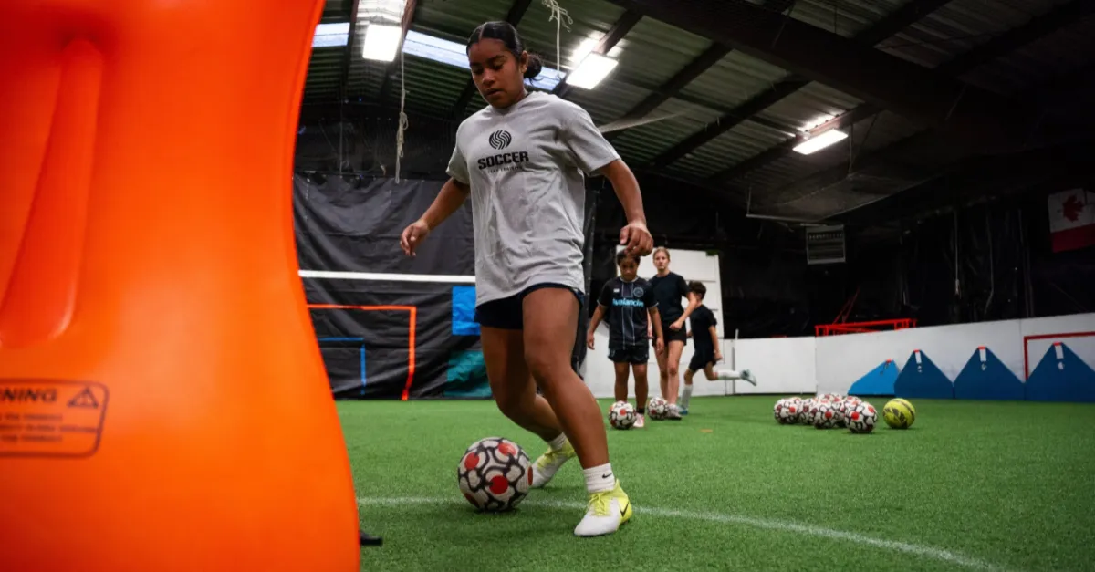 Kids playing soccer with a coach during practice