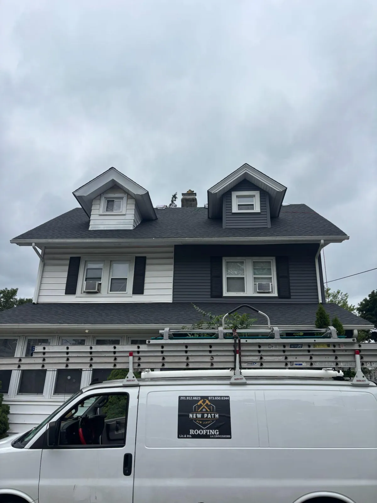  Front view of a residential home in Passaic County, NJ with new roof replacement, professional gutter cleaning, and vinyl siding installation completed by New Path Roofing
