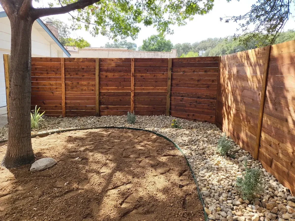 Wood privacy fence surrounding a landscaped yard.