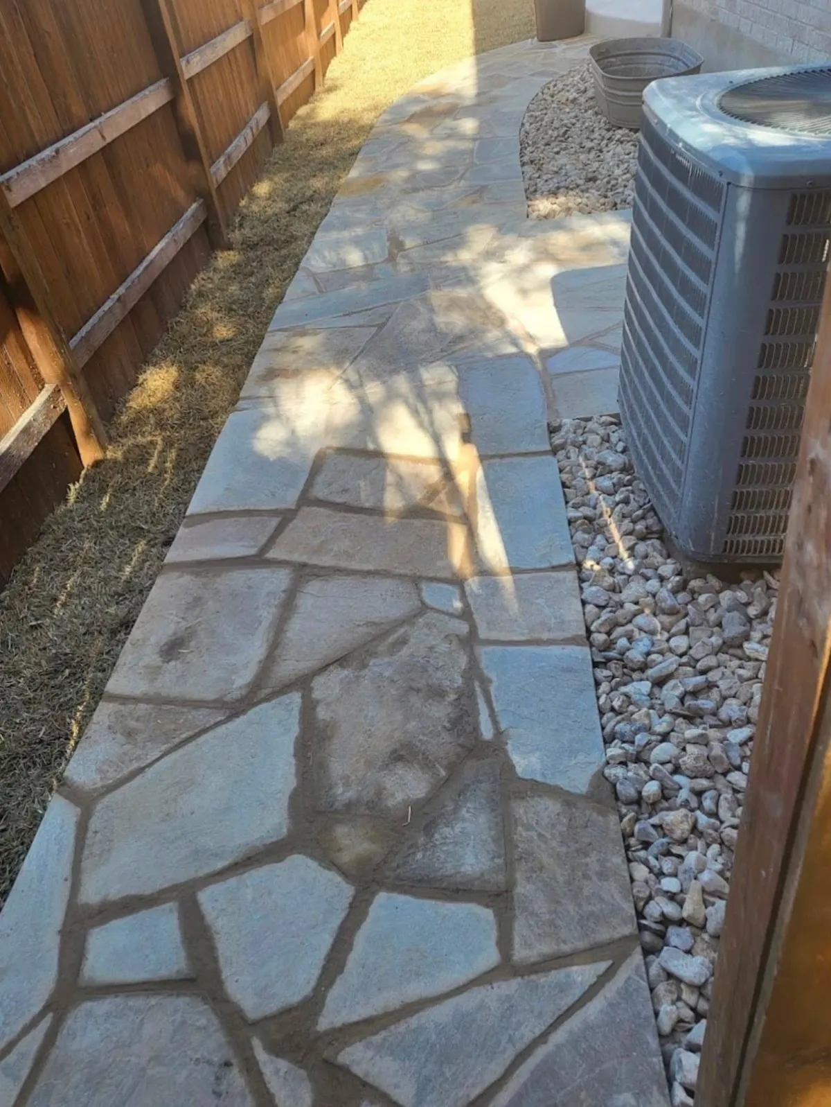 Stone walkway with decorative rock along a residential yard.