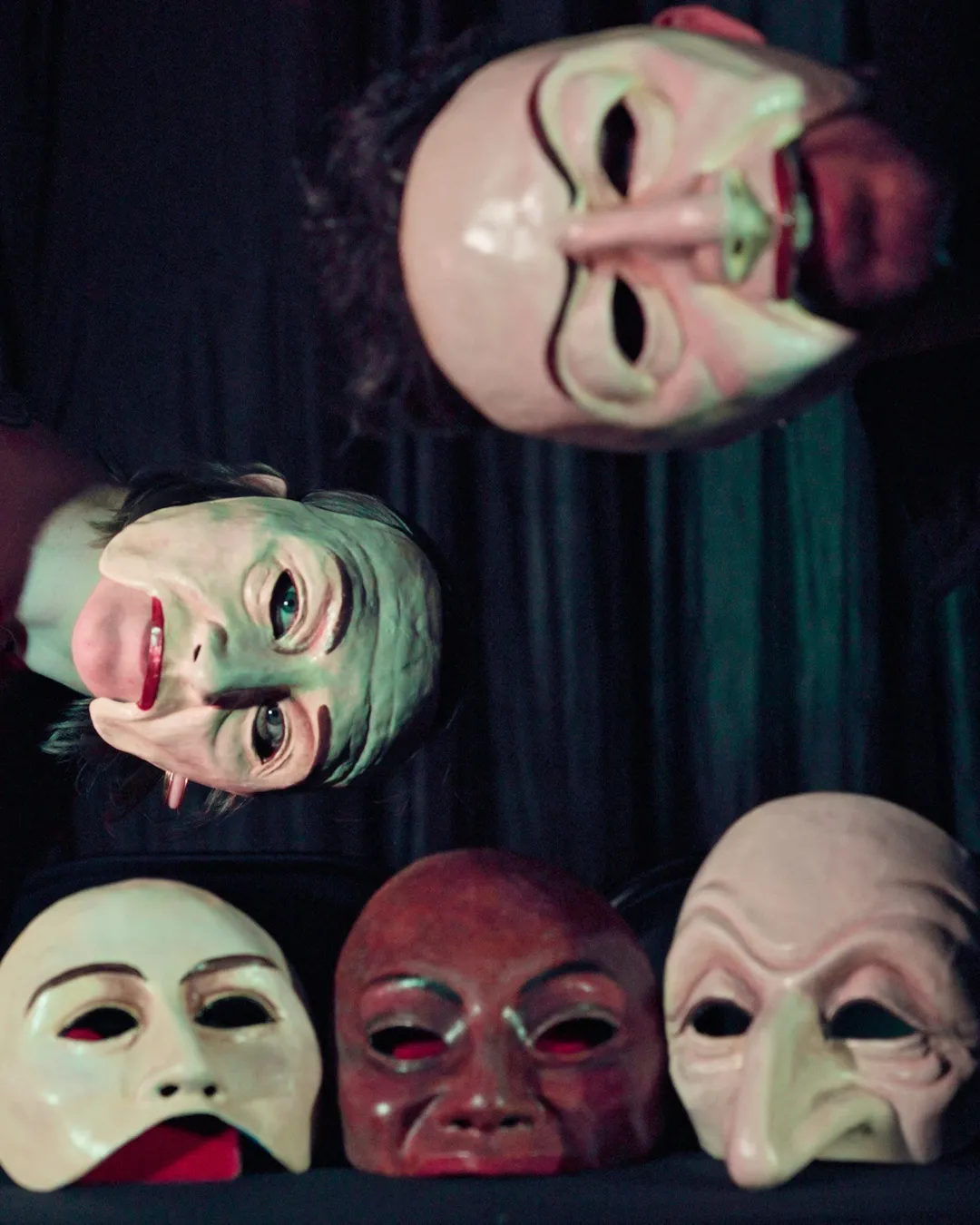 A candid group portrait of the 8 Seasons creative team gathered around a rehearsal table, animatedly discussing scripts and stage designs. The diverse group includes men and women of various ages and backgrounds, with sketches, props, and coffee cups scattered across the table, set in a warmly lit backstage studio.