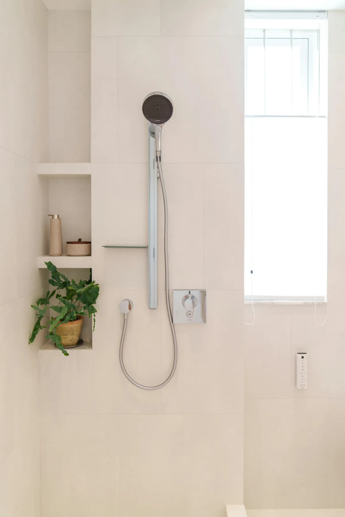 bathroom shower head on wall with cream tiles