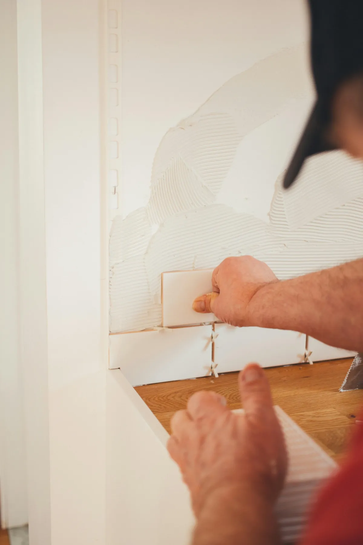 contractor laying white tiles on wall 