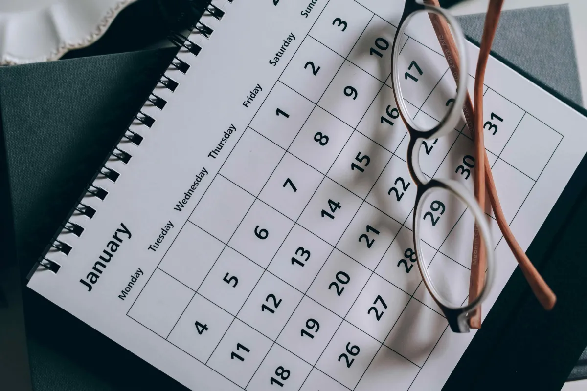 A calendar with glasses and a pen resting on it, illustrating organized scheduling to keep a steady flow of ready-to-book leads