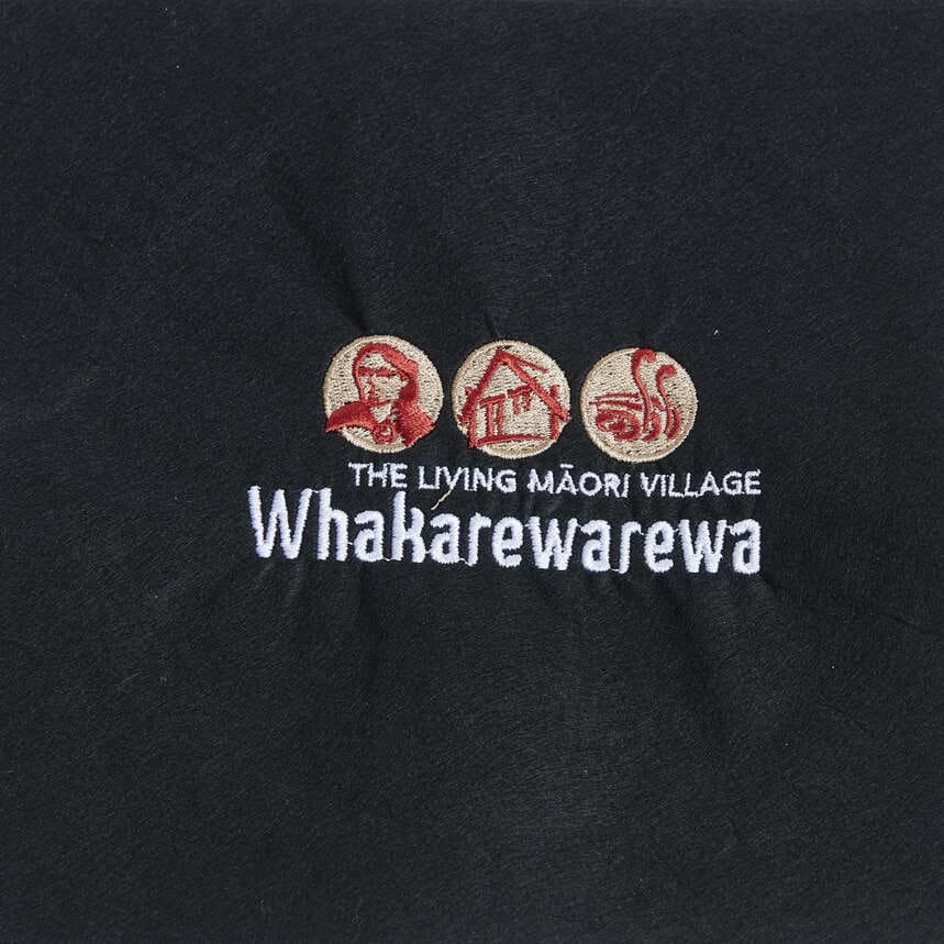 Whakarewarewa The Living Māori Village logo embroidered in red, beige and white on black fabric