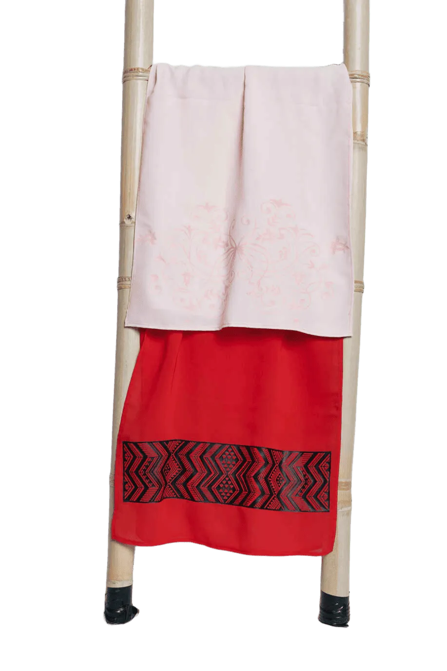 Pale pink and red textiles with decorative patterned detailing on bamboo ladder
