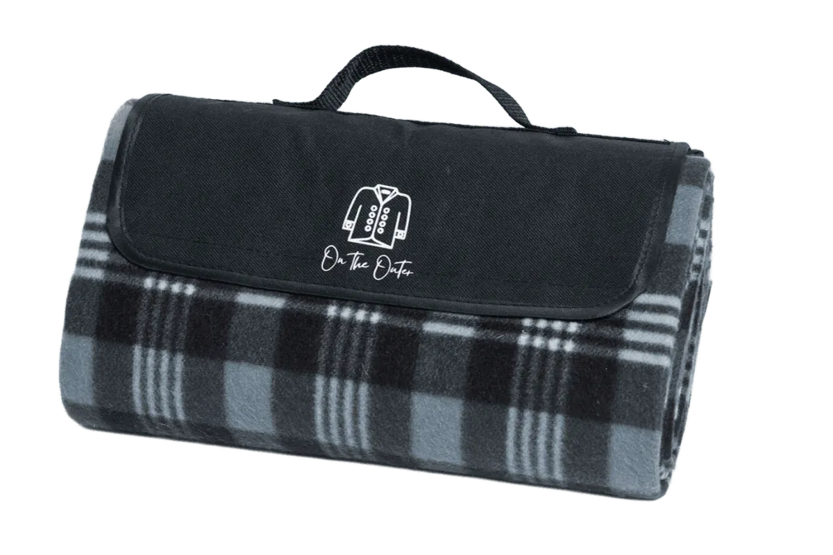 Grey plaid picnic blanket with black flap and white On the Outer logo