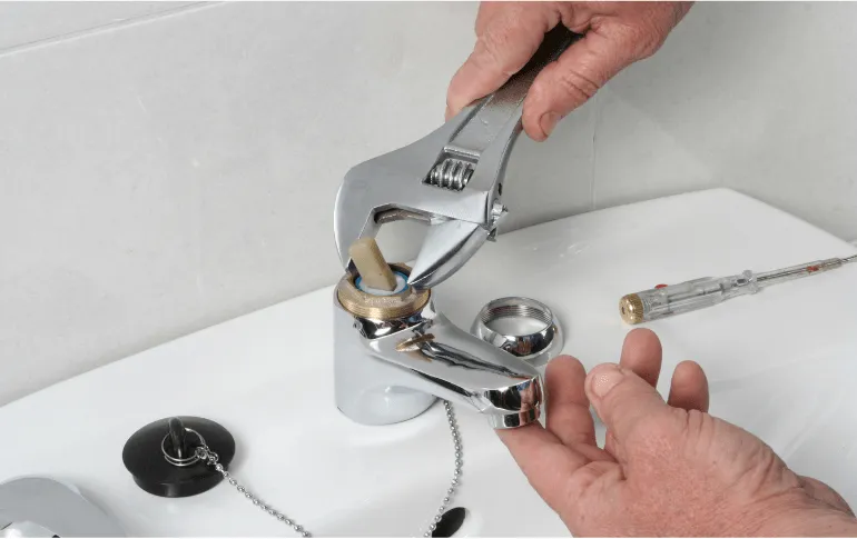 Plumber repairing a bathroom sink faucet using a wrench – Professional faucet repair services in San Antonio, TX by 2nd Opinion Plumbing.