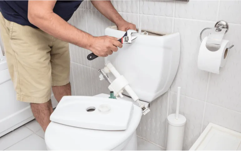 Plumber repairing a toilet tank using a wrench – Professional toilet repair services in San Antonio, TX by 2nd Opinion Plumbing.