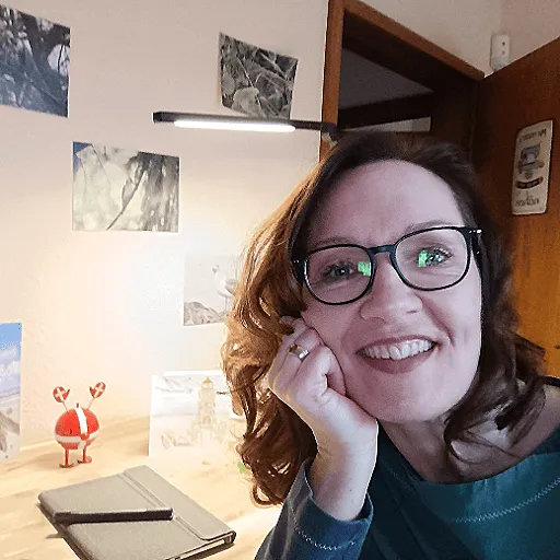Katja mit Zwinkern, Hoptimist-Figur und Mini-Journal vor Sonnenuntergang an der Nordsee – Symbol für Leichtigkeit, Inspiration und kreativen Rückzug.