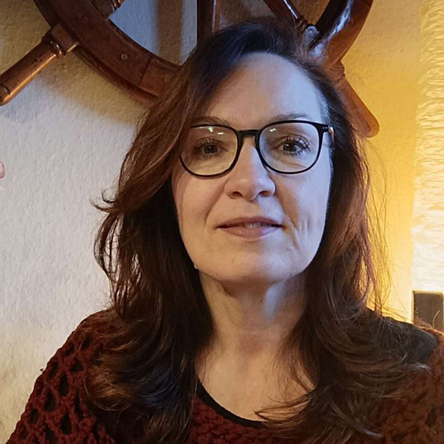 Katja mit Zwinkern, Hoptimist-Figur und Mini-Journal vor Sonnenuntergang an der Nordsee – Symbol für Leichtigkeit, Inspiration und kreativen Rückzug.