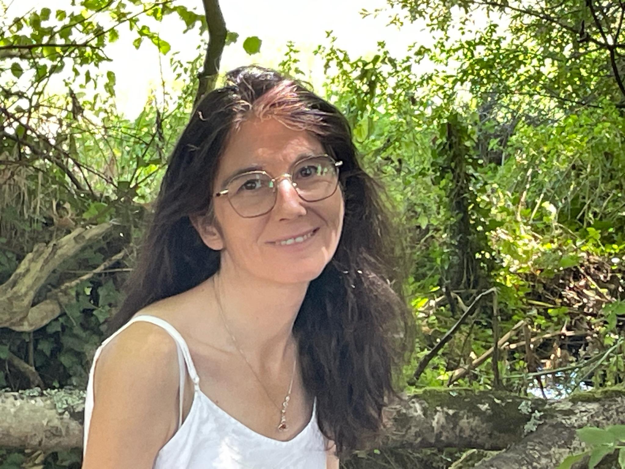 Femme brune écrivant près d’une fenêtre face à la mer, symbole d’introspection et de retour à soi Pour l’icône “Cheffe de tribu” :