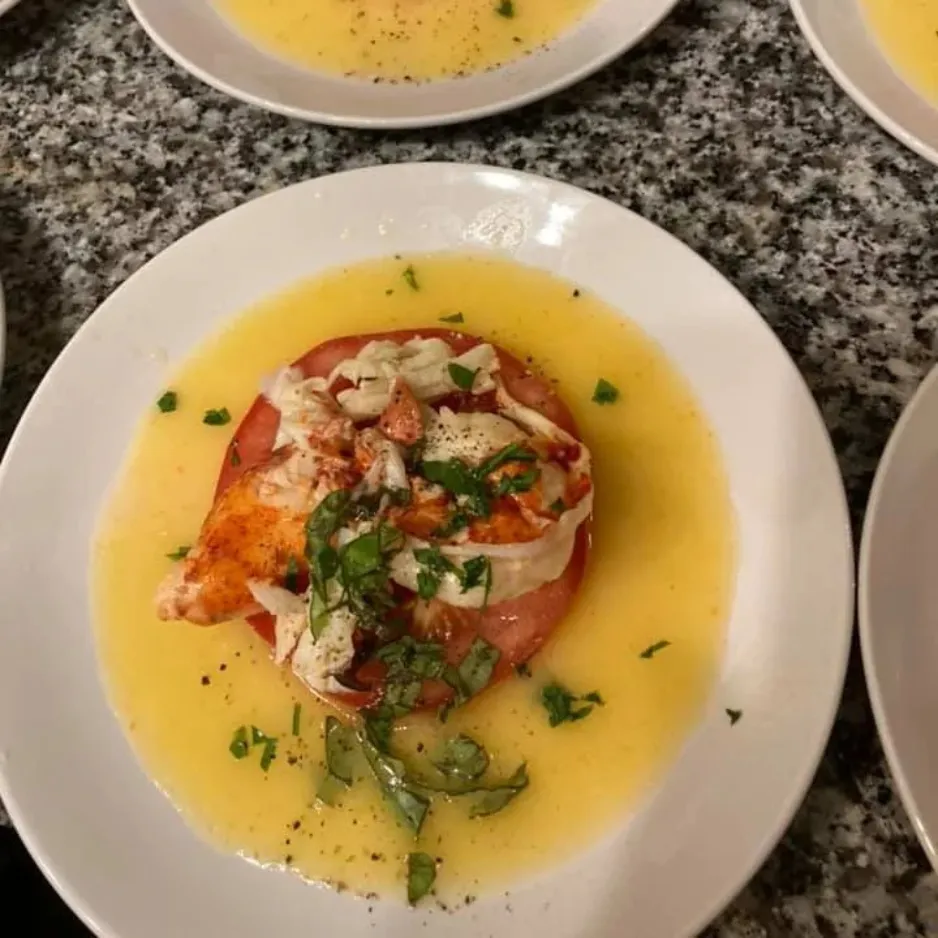 A refined seafood tartar served over a thick slice of heirloom tomato in a bright citrus reduction sauce.