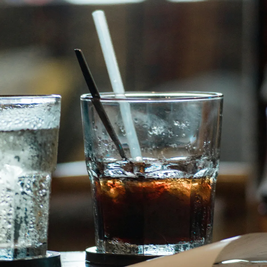 Classic mixed drinks and ice-cold refreshments served in highball glasses at a high-volume wedding reception bar.