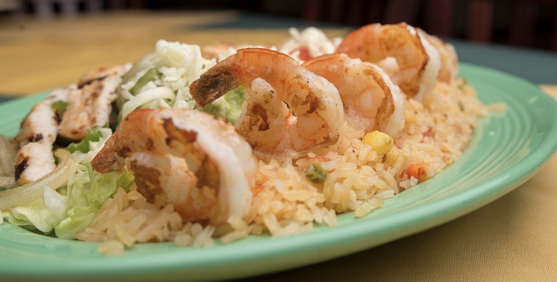 Chef's hands plating fajitas with a squeeze of lime, motion captured in warm kitchen light.