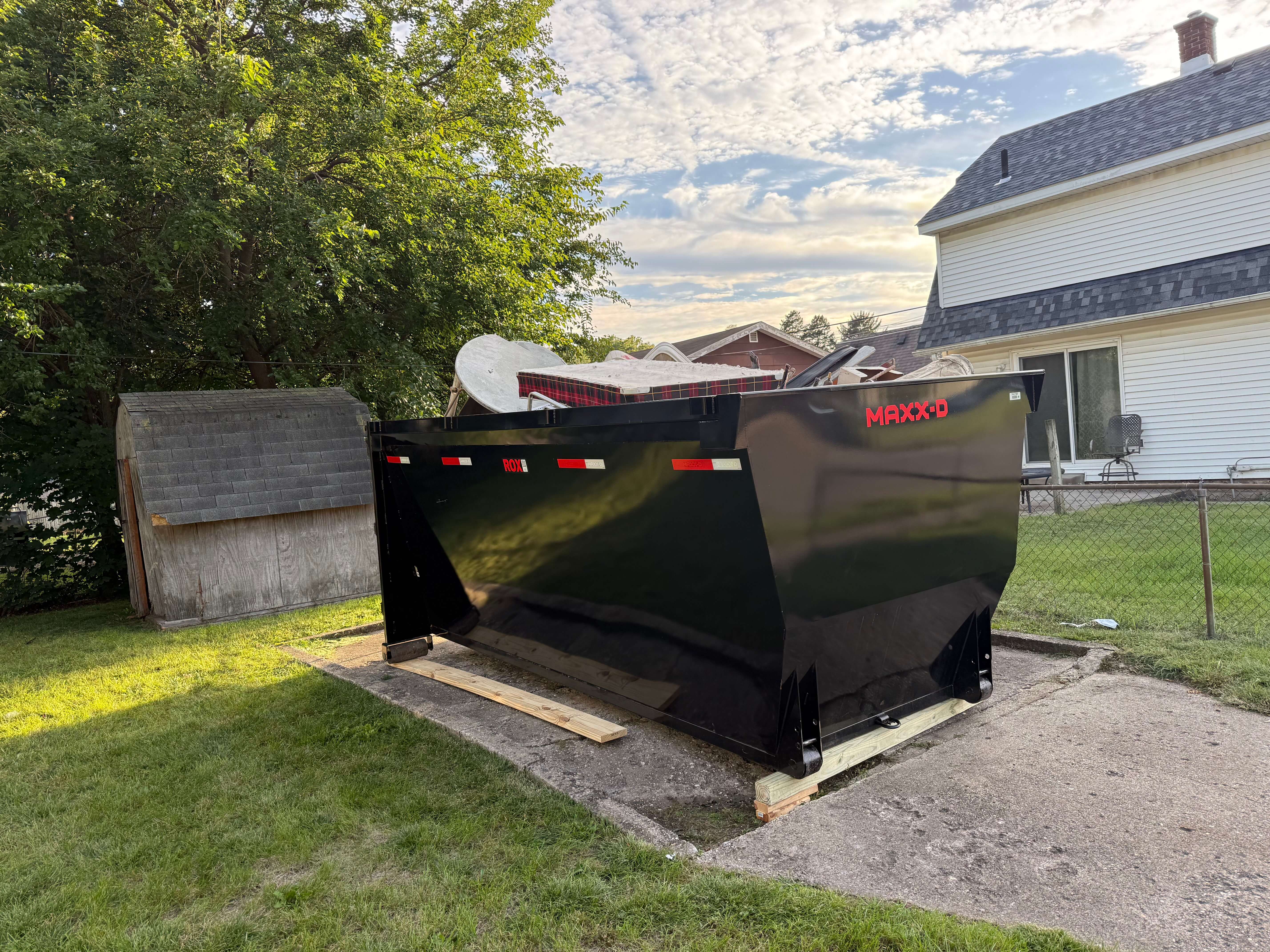 Heavy duty commercial dumpster parked safely on a clean residential driveway
