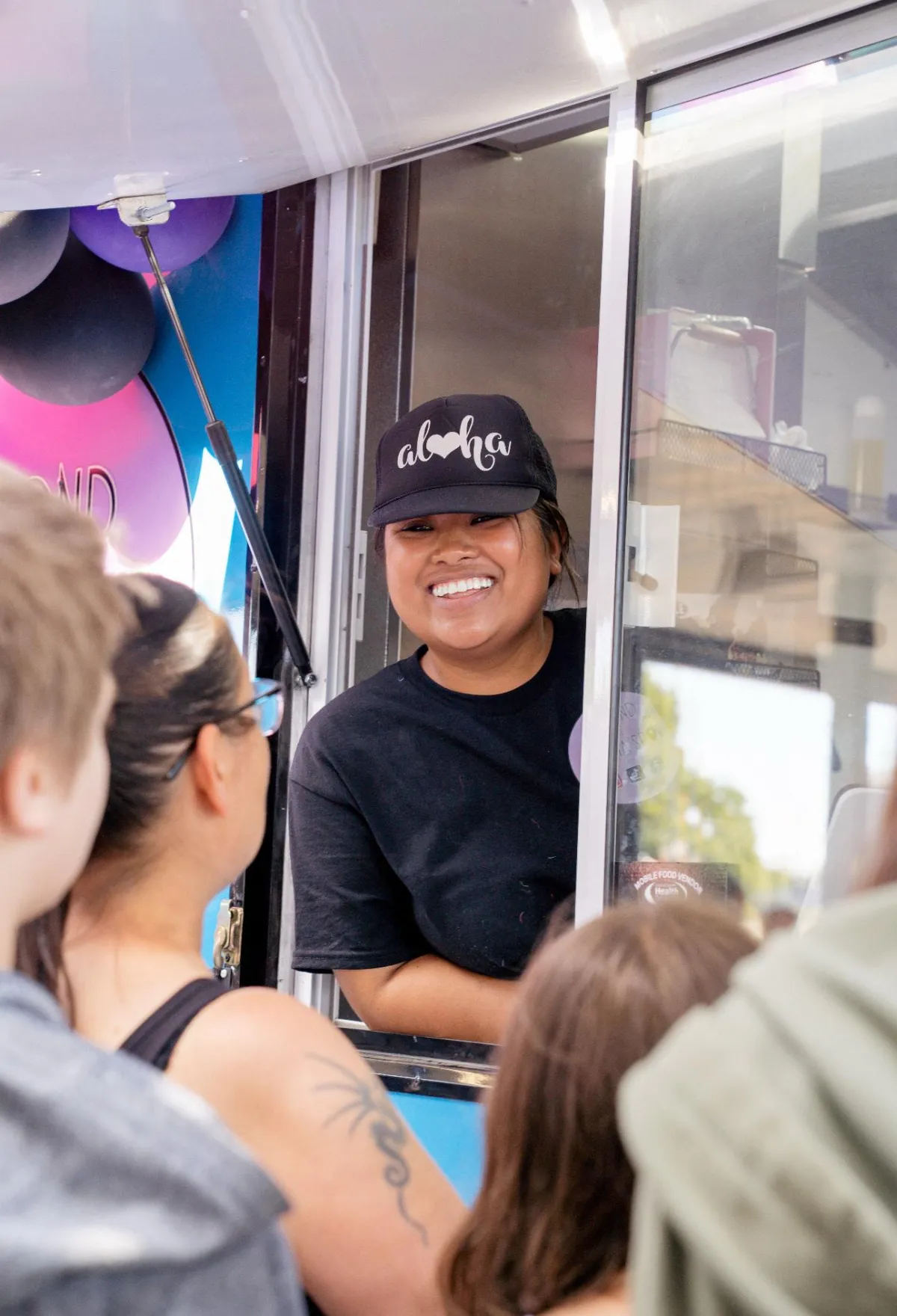 Sam and Lia, Filipino-American siblings, casual attire, laughing, food truck window, palm leaves visible