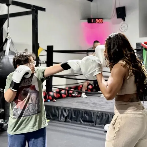 BoxingRX coach holding pads for a young boxer
